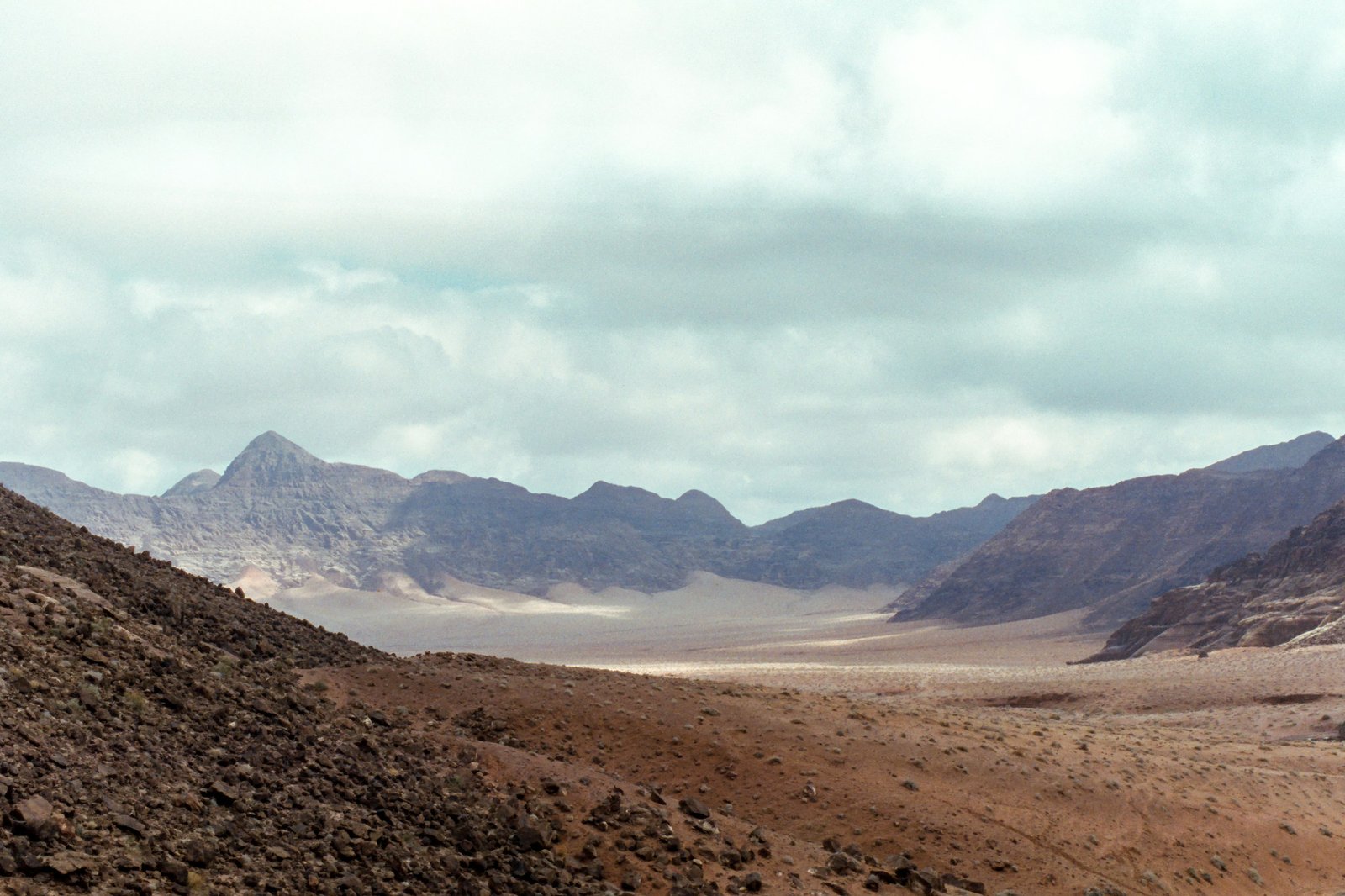 Red sandstone mountains rising from the open desert of Wadi Rum