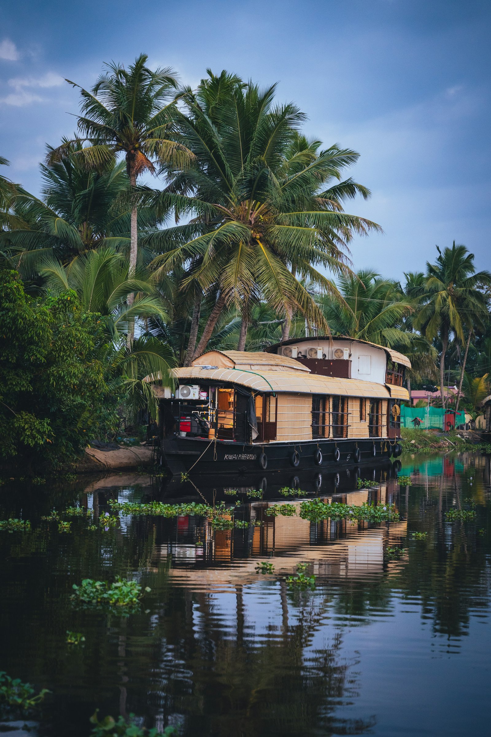 A traditional houseboat moving through palm-lined Kerala backwaters